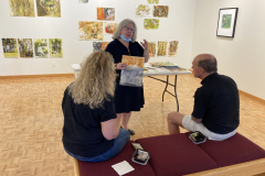 Image of artist giving lecture in gallery, showing examples of how she makes her artwork.