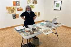 Image of artist giving lecture in gallery, showing examples of how she makes her artwork.