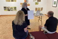 Image of artist giving lecture in gallery, showing examples of how she makes her artwork.
