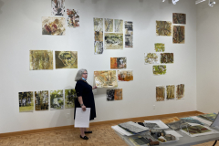Image of artist giving lecture in gallery, showing examples of how she makes her artwork.