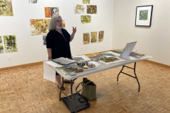 Image of artist giving lecture in gallery, showing examples of how she makes her artwork.