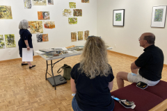 Image of artist giving lecture in gallery, showing examples of how she makes her artwork.