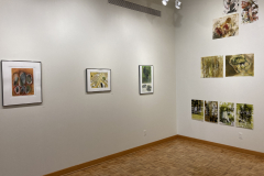 Installation shot of gallery, showing rear left corner, on the right are prints hung in groupings, on the left are three framed prints hung evenly on the wall.