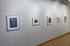 Installation shot of gallery, showing the left wall of the gallery, with five framed prints hung evenly on the wall.