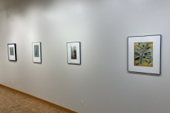 Installation shot of gallery, showing the right wall of the gallery, with four framed prints hung evenly on the wall.