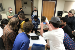 Image from Jenn Libby's Wet Collodion Demonstration. This image shows the students circled around a photographic tray with the final image in i.