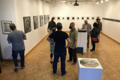 Image from the opening reception for Jenn Libby's exhibition Echoes from the Ether. This image shows a group of people standing near some photographs, talking.