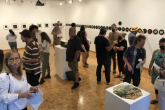 Image from the opening reception for Jenn Libby's exhibition Echoes from the Ether. This image shows a group of people standing near some photographs, talking.