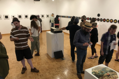 Image from the opening reception for Jenn Libby's exhibition Echoes from the Ether. This image shows a group of people standing near some photographs, talking.