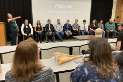 A group of people sit at the front of a room, discussing the film with the crowd.