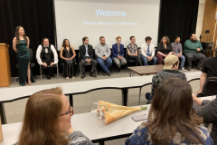 A group of people sit at the front of a room, discussing the film with the crowd.