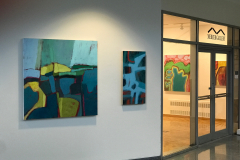 Installation shot of Judy Gohringers Mercer Gallery exhibition. In this image, we are outside the gallery. There are two colorful landscape paintings on the right of the image. On the left side we see the entrance to the gallery and two more paintings inside the gallery on a wall.