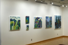 Installation shot of Judy Gohringers Mercer Gallery exhibition. This image shows the back portion of the left wall, which  contains six colorful landscape paintings of various sizes.