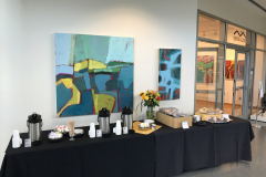 Photograph from the opening reception for Judy Gohringer. This image shows the food table outside the gallery with two of her paintings on the wall above it.