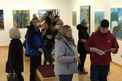Photograph from the opening reception for Judy Gohringer. This image shows a group of visitors looking at the art work on the wall, some people are talking with others.