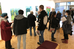 Photograph from the opening reception for Judy Gohringer. This image shows a group of visitors looking at the art work on the wall, some people are talking with others.
