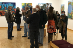 Photograph from the opening reception for Judy Gohringer. This image shows a group of visitors looking at the art work on the wall, some people are talking with others.