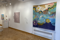 The right gallery wall, with a variety of colorful paintings, and a fun painting on the wall outlining the heating duct.