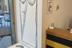 Small area in the gallery, showing a wall painting and a small ink drawing.