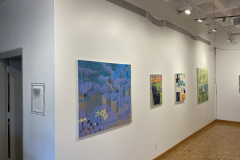 The gallery wall on the left, showing a variety of colorful paintings in various sizes.