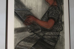Installation shot of an image of a woman working with a loom.