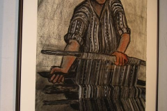 Installation shot of an image of a woman working with a loom.