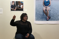 Monica Frisell talking about her work in the Mercer Gallery. She sits in front of two prints hanging on the wall.