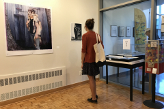 A woman looking at a large Monica Frisell portrait.