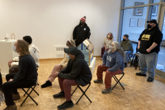 A photograph of guests sitting in chairs in the gallery.