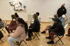 A photograph of guests sitting in chairs in the gallery.