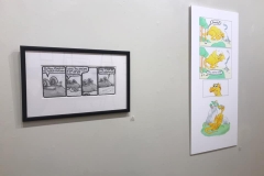 Installation shot of right gallery wall containing 2 comic illustrations.