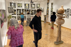 Photograph from the artist reception for Patti Russotti. People look at various art on the walls.