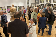 Photograph from the artist reception for Patti Russotti. Large groups of people talk in the gallery while others look at the art on the walls..