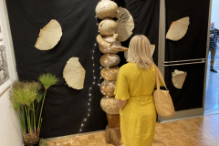 Photograph from the artist reception for Patti Russotti. A person looks at a sculpture.