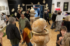 Photograph from the artist reception for Patti Russotti. Large groups of people talk in the gallery while others look at the art on the walls..