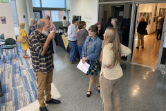 Photograph from the artist reception for Patti Russotti. Groups of people stand outside the gallery, talking and enjoying food and beverage.