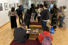 An image from the opening reception, in which many people listen to an artist speaking.