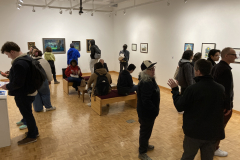 An image from the opening reception, in which many people look at artwork.