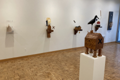 Detail image of the Robert Booth gallery installation, showing the right wall and five wall sculptures hanging, and one floor sculpture on a pedestal.