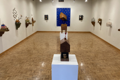 Detail image of the Robert Booth gallery installation, showing most of the gallery, including the left wall and four sculptures hanging, the rear wall and three sculptures hanging and the right wall with three sculptures hanging. There are also three floor sculptures positioned on pedestals down th emiddle of the floor in the center of the photograph.