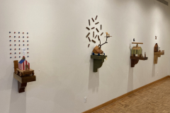 Detail image of the Robert Booth gallery installation, showing a detail of the left wall and the four sculptures hanging there.