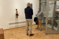 An image of the opening reception for Robert Booth. In this image we see a corner of the gallery, and two people talking with two sculptures in the background .