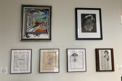 Small wall of framed drawings and paintings by Tom Mercer.