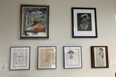 Small wall of framed drawings and paintings by Tom Mercer.