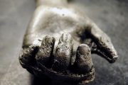 Detail view of cast aluminum hand on dark ground.