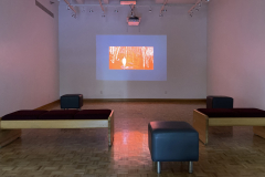 Installation shot of gallery showing video projected on rear wall.